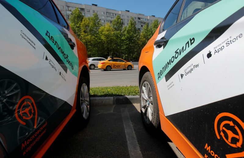FILE PHOTO: Taxi car drives by Delimobil branded vehicles in