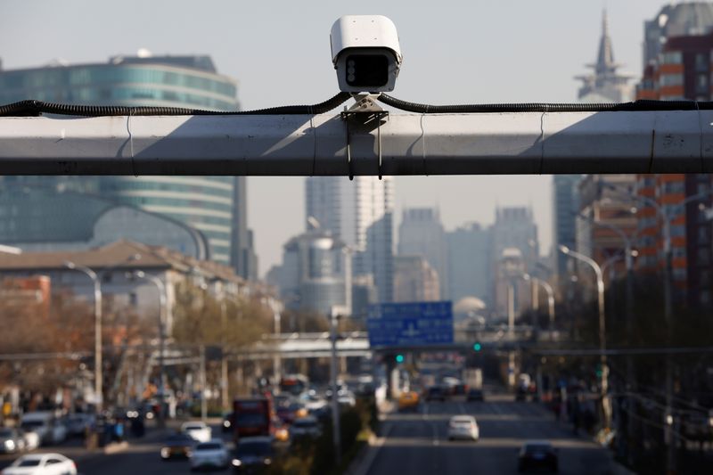 A security surveillance camera overlooks a street as cars drive