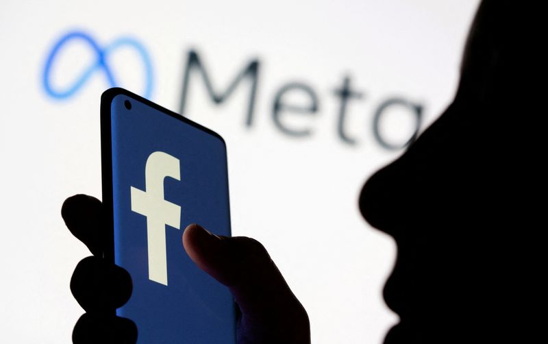 FILE PHOTO: Woman holds smartphone with Facebook logo in front