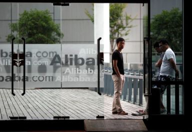 Employees stand next to a glass door with logos of