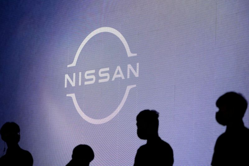FILE PHOTO: People stand near the Nissan logo during a