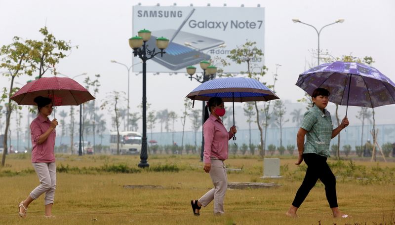 FILE PHOTO: Employees pass a billboard advertisement for the Samsung