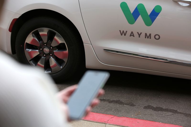A Waymo employee hails a ride on their phone during