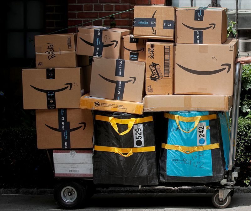 An Amazon delivery worker pulls a delivery cart full of