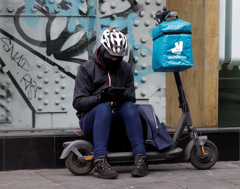 A Deliveroo rider sits outside a fast food restaurant in
