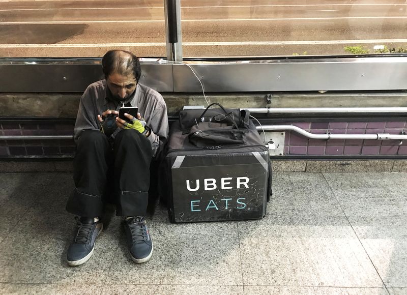 An Uber Eats worker checks his mobile phone in Sao