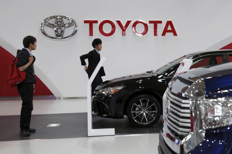 People walk under a logo of Toyota Motor Corp at