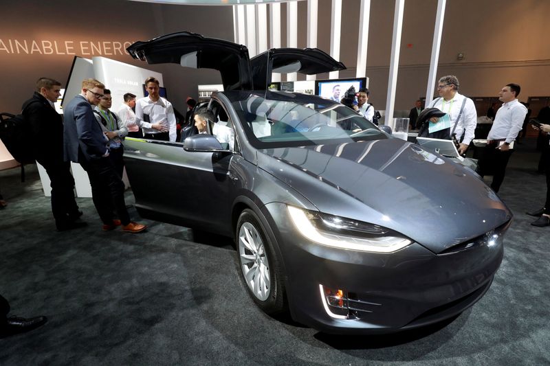 Attendees look over a Tesla Model X powered by Panasonic