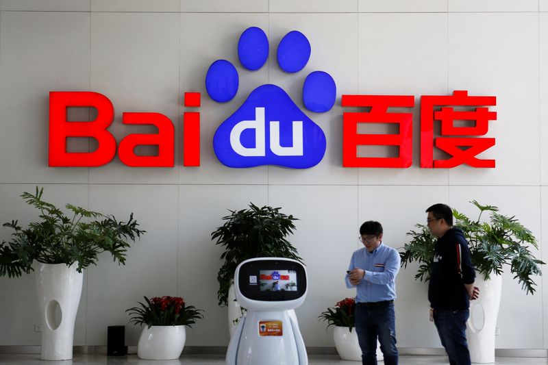 Men interact with a Baidu AI robot near the company