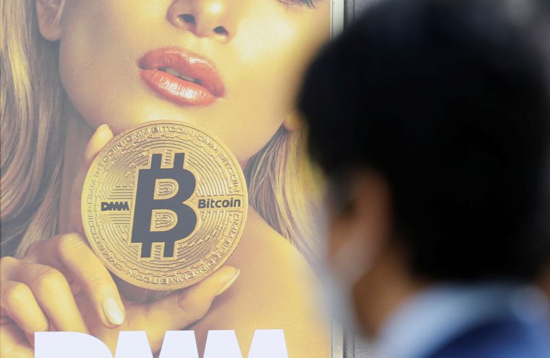 A man stands near an advertisement of a cryptocurrency exchange