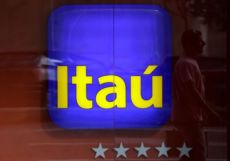 FILE PHOTO: Man is reflected in an Itau branch window
