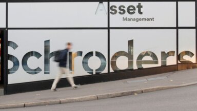 FILE PHOTO: A man walks past the logo of investment