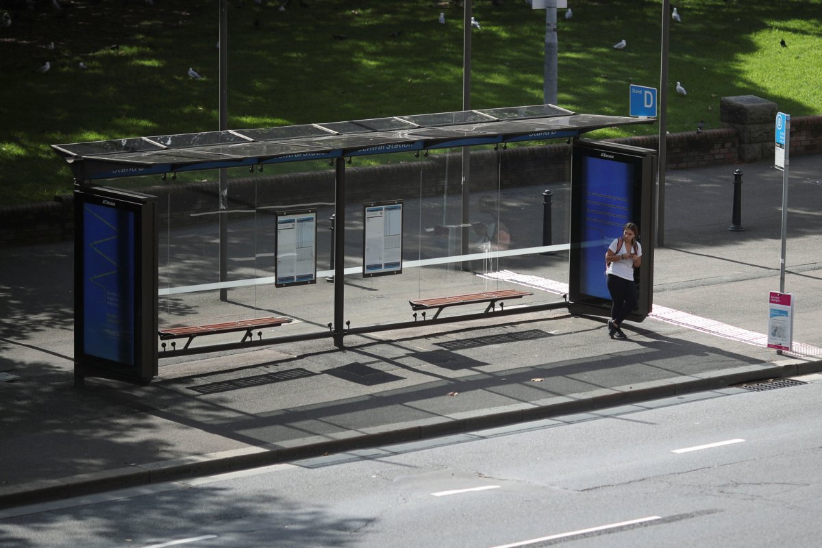 A woman stands alone on a bus stop during a