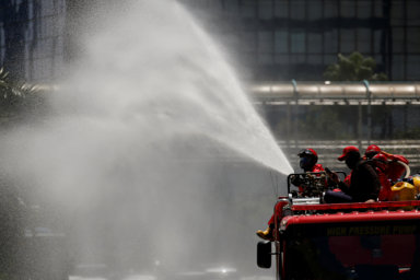 Firefighters spray disinfectant using high pressure pump truck to prevent