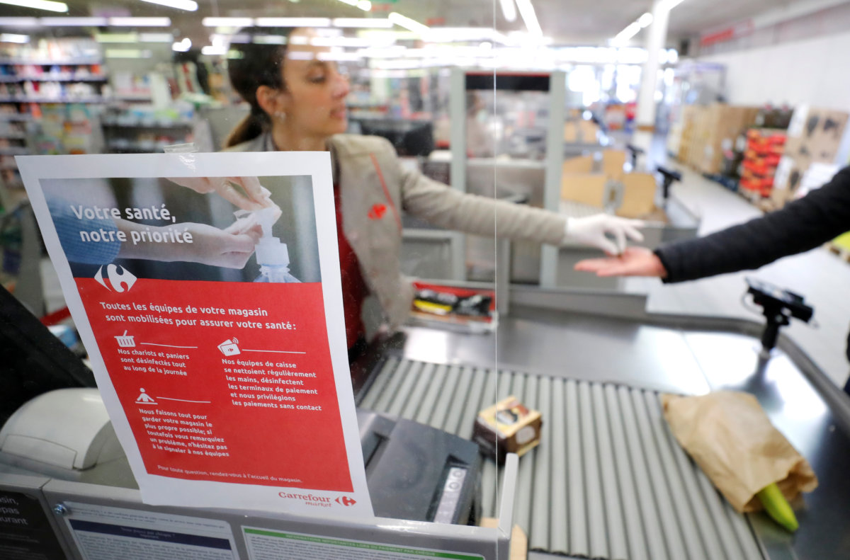 A cashier serves a customer behind a plastic protection shield