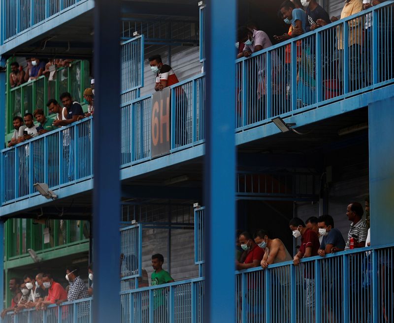 FILE PHOTO: Migrant workers look out from their balconies at