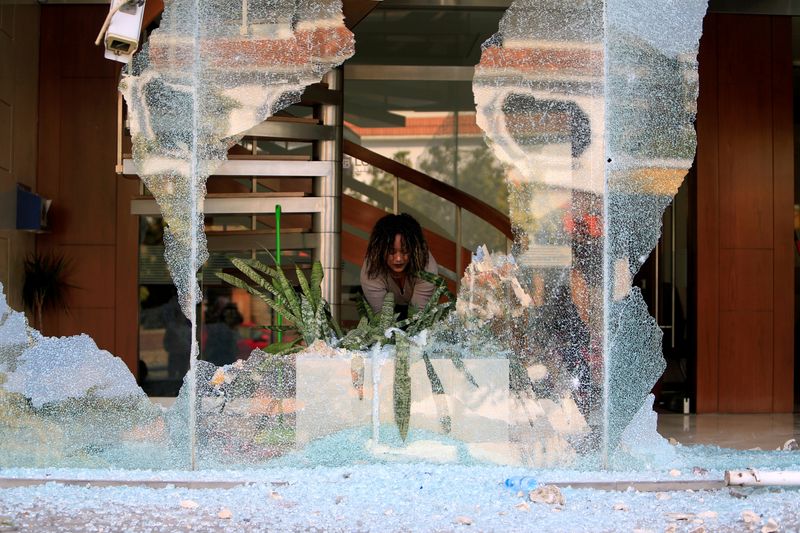 Worker cleans up broken glass from a bank facade after
