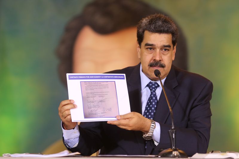 Venezuela’s President Nicolas Maduro holds a document during a virtual