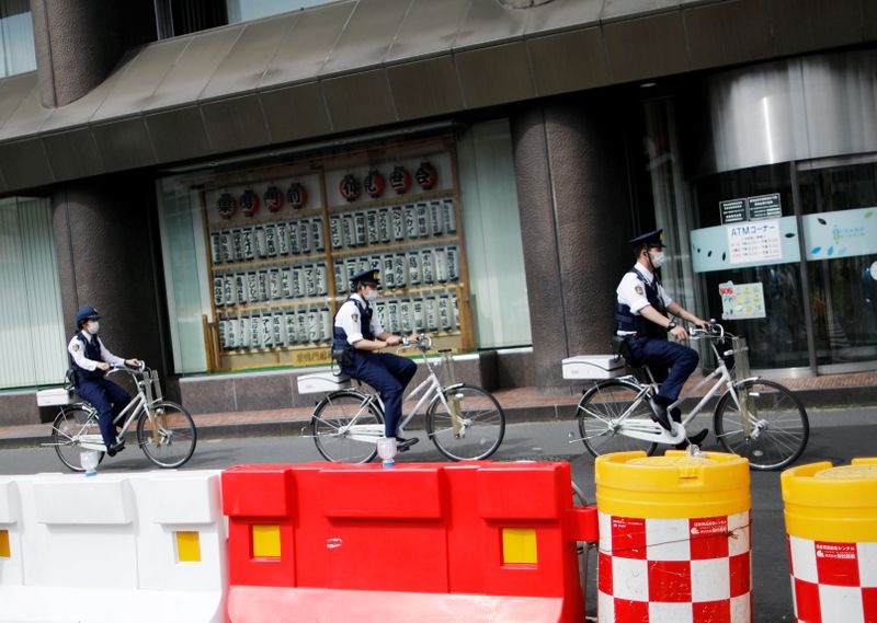 Police officers wearing protective face masks ride bicycles on the