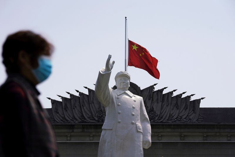 he Chinese national flag flies at half-mast behind a statue