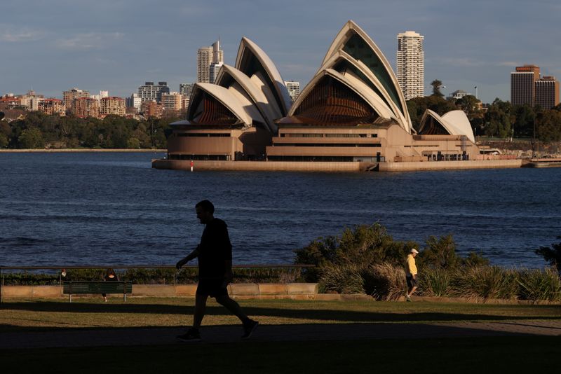 People stroll through a park in front of the Sydney