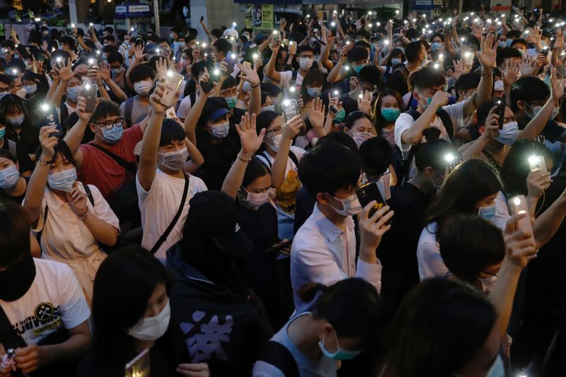 Pro-democracy demonstrators march holding their phones with flashlights on during