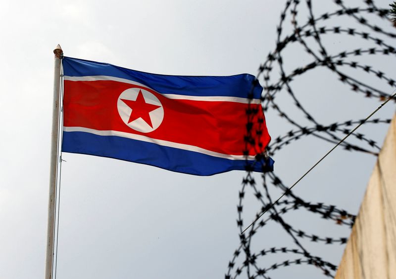 The North Korea flag flutters next to concertina wire at