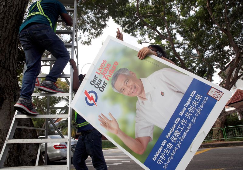 FILE PHOTO: Workers hang up electoral posters ahead of the