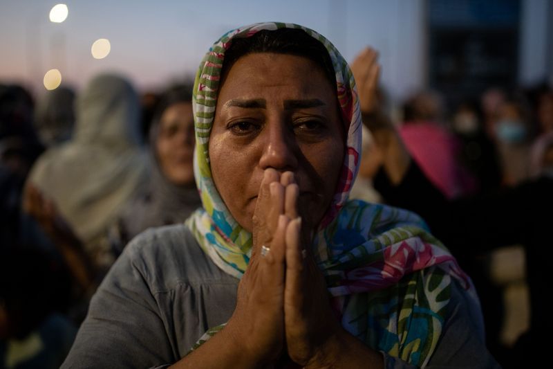 A woman reacts as refugees and migrants from the destroyed