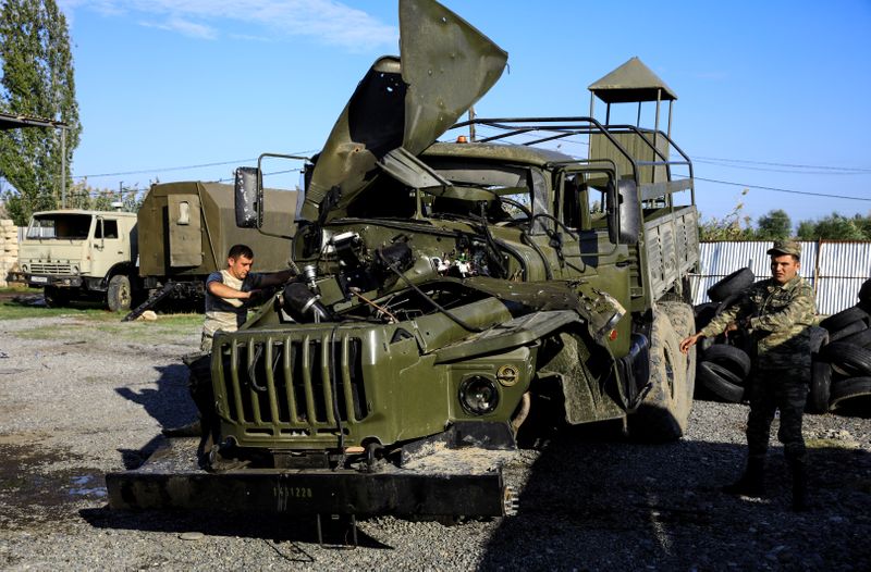Soldiers inspect a damaged Armenian military truck seized by Azerbaijan