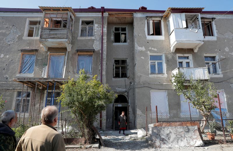 Men stand at their house damaged by recent shelling during