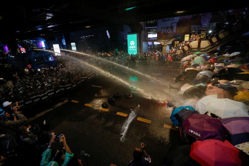People are hit with water from water cannons during an