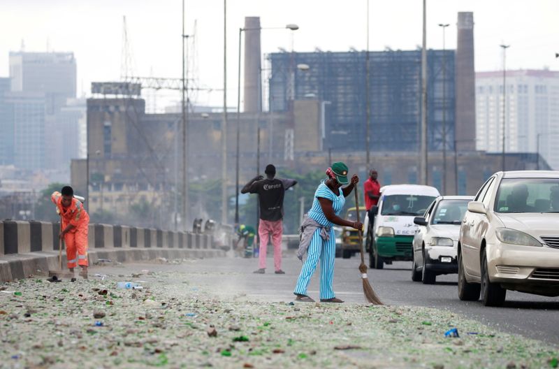 Cars drive as people clean the streets in Lagos