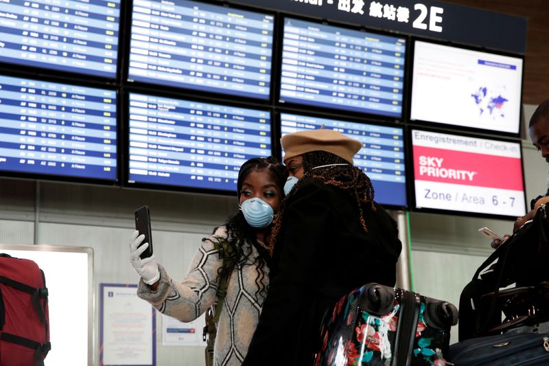 FILE PHOTO: Travellers wearing protective face masks stand inside Terminal