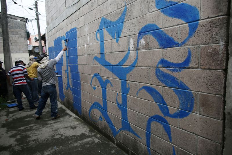 FILE PHOTO: Police officers paint off a graffiti related to