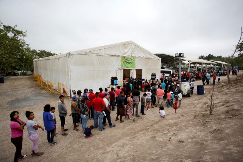 FILE PHOTO: Migrants seeking asylum in the U.S. queue for