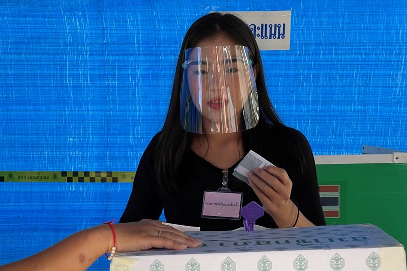 A woman wearing a face shield votes in the provincial