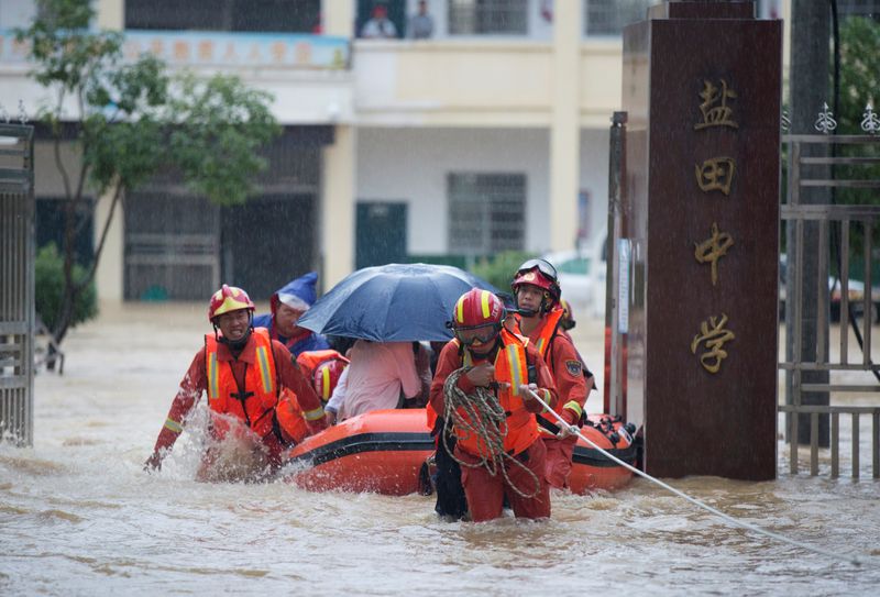 Rescue workers evacuate students stranded by floodwaters at a school,