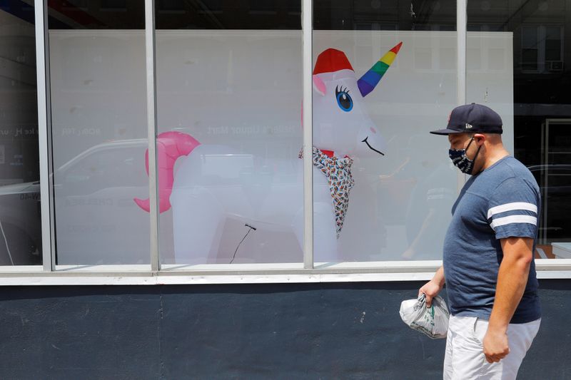 A pedestrian passes a storefront with an inflated unicorn in