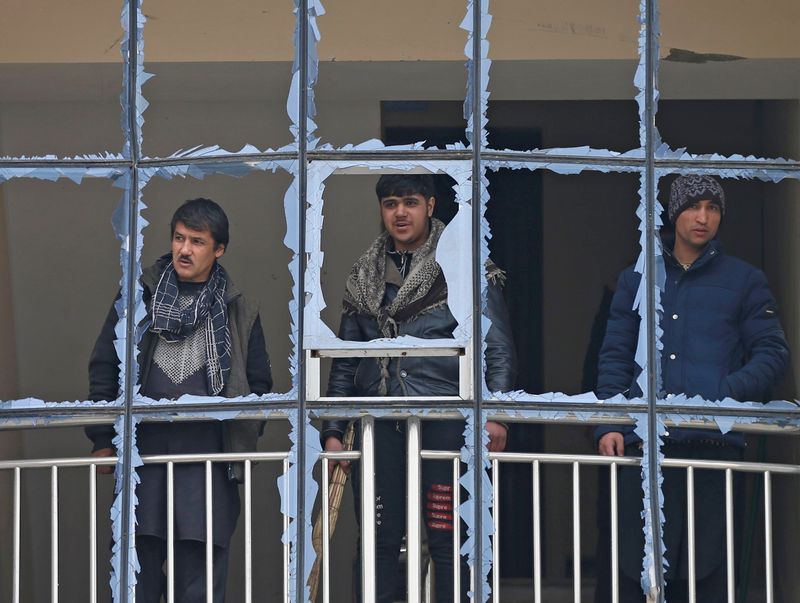 FILE PHOTO: Afghan men look out from a damaged window
