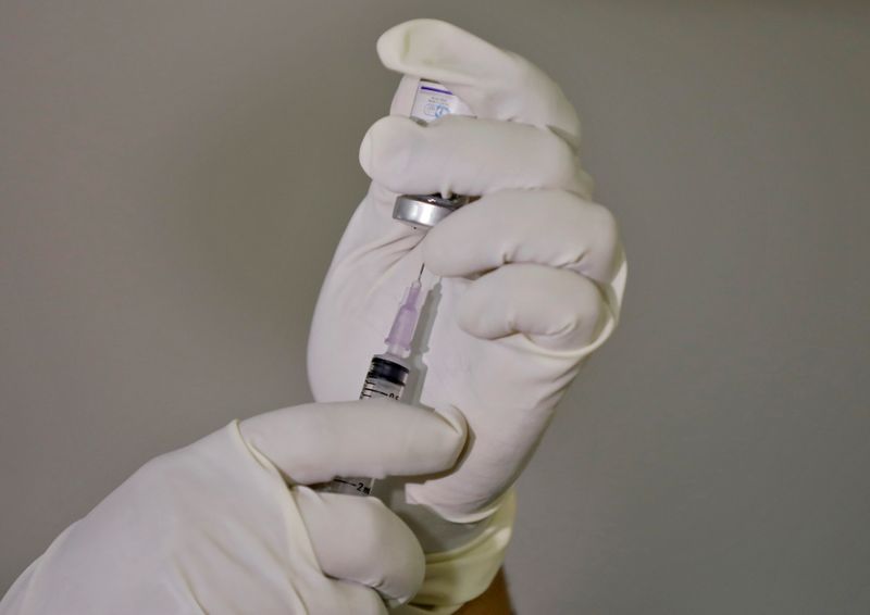 A paramedic fills a syringe with a vaccine against the