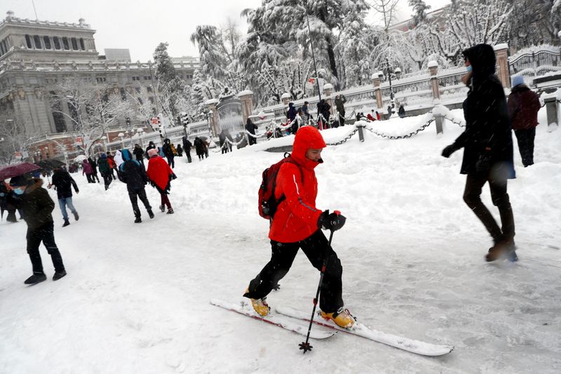 People walk and ski downtown during a heavy snowfall in