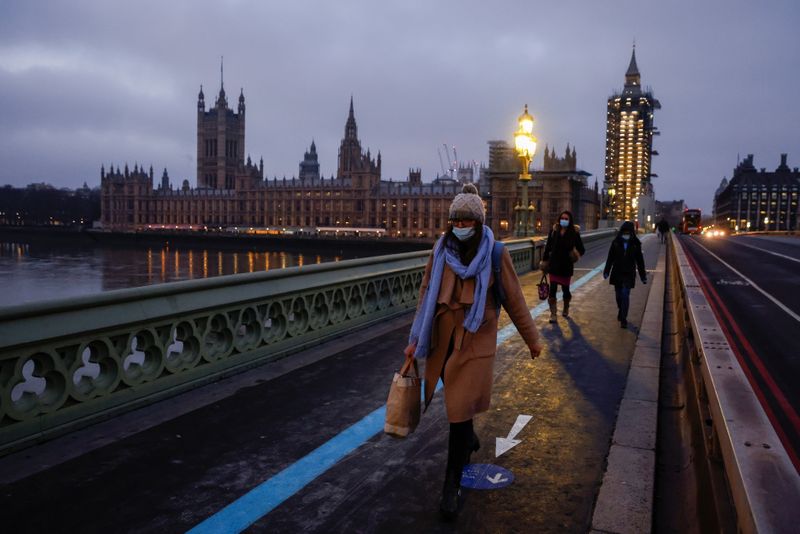 People wearing face masks cross Westminster Bridge in London