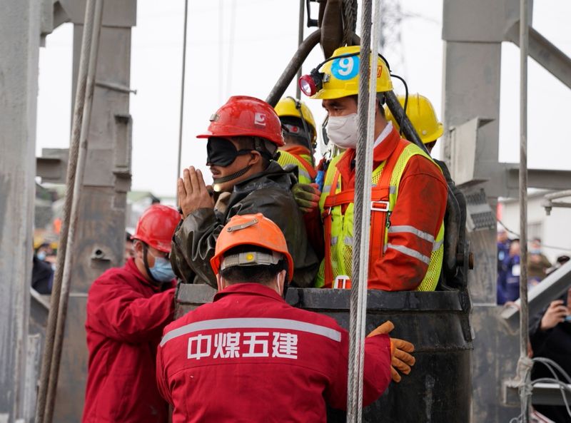 Rescue workers help a miner at the Hushan gold mine
