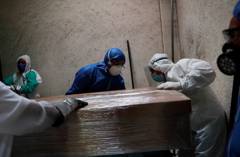 Funeral and crematorium employees work on a coffin carrying the