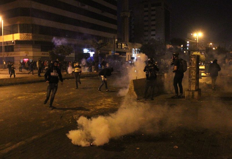 Demonstrators are pictured near smoke rising from tear gas during