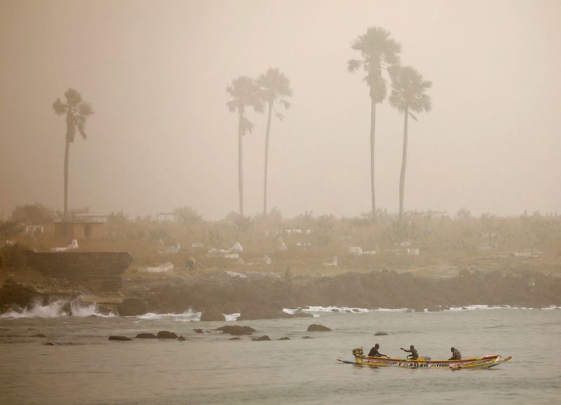 Fishermen are pictured on their pirogue as dust carried by