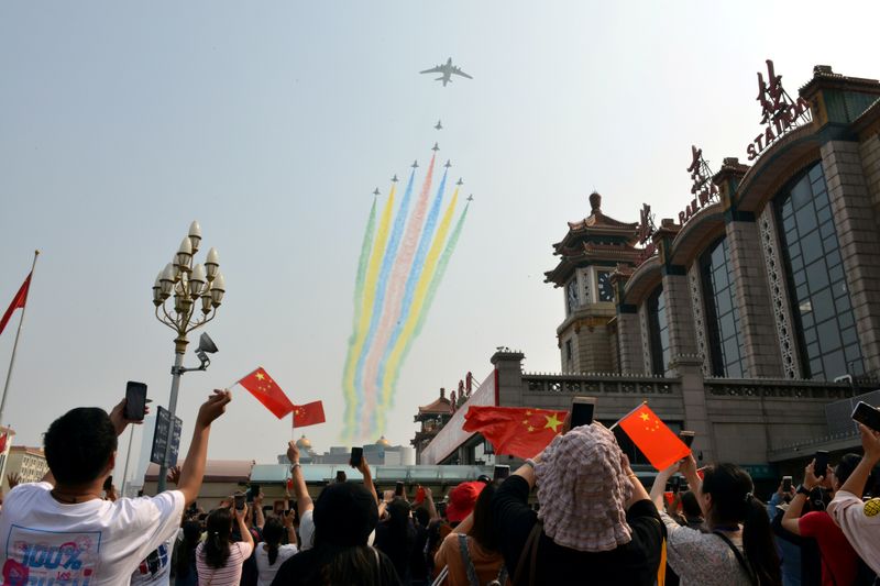 FILE PHOTO: People hold their mobile phones and Chinese flags