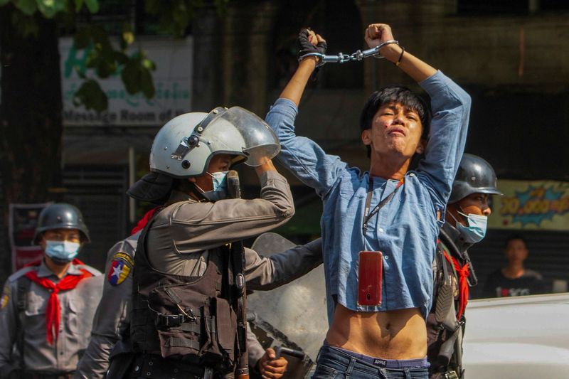 A pro-democracy protester is detained by riot police officers during