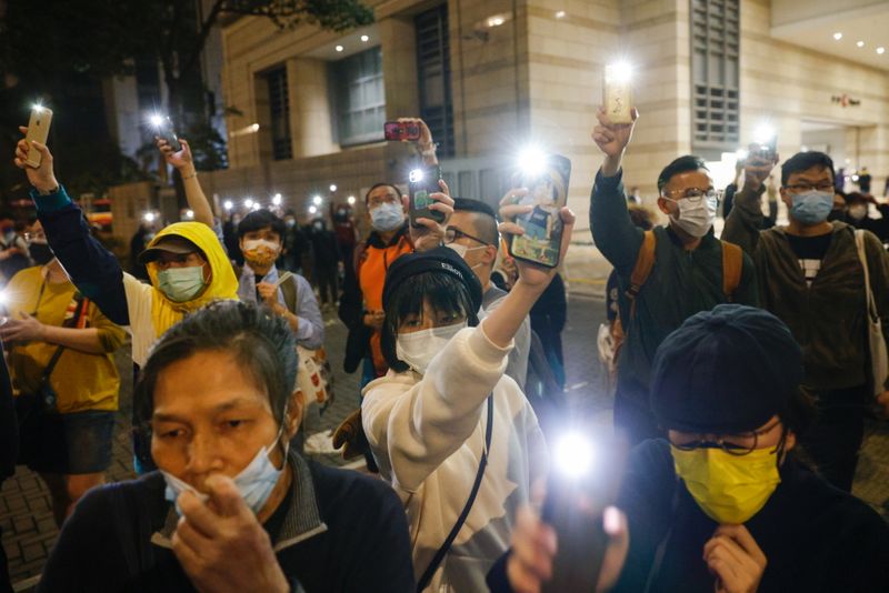 Supporters of pro-democracy activists hold flashlights as they wait for